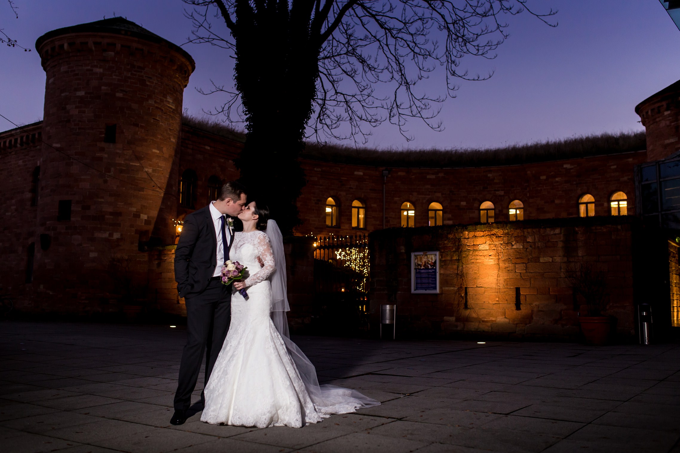 Hochzeitspaar küsst sich vor einem spektakulären lila Himmel vor dem Hyatt Regency Hotel in Mainz