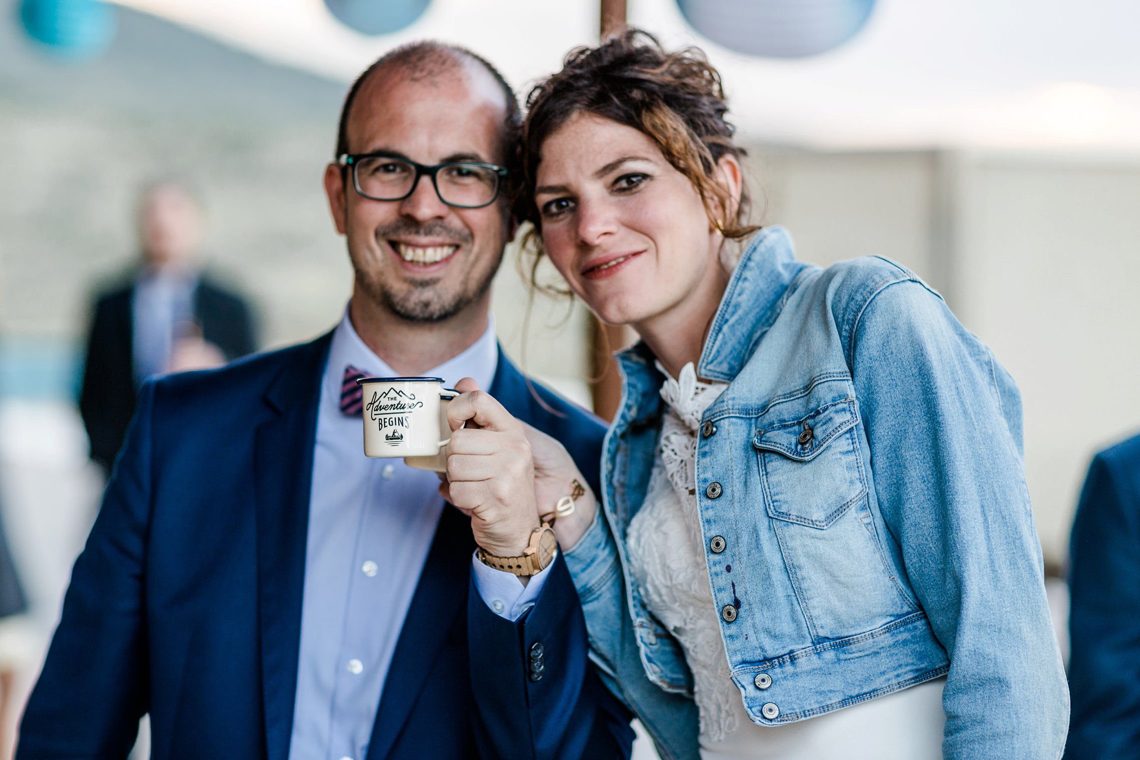 Das Hochzeitspaar hält eine Tasse mit der Inschrift: The adventure begins