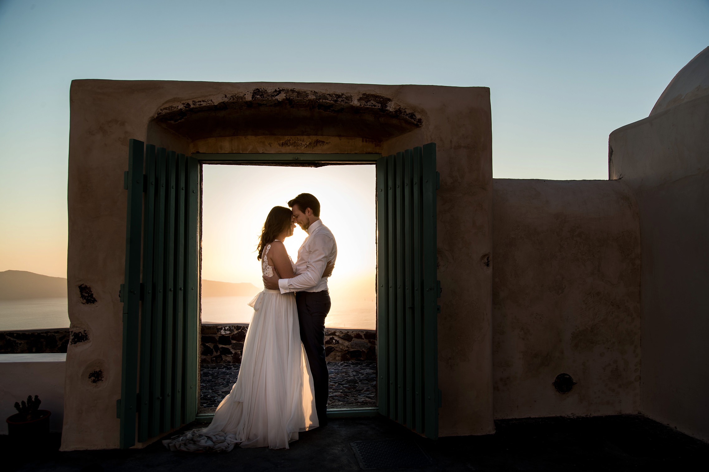 Brautpaar steht in einem Türrahmen in Imerovigli auf Santorini - Elopement in Griechenland.