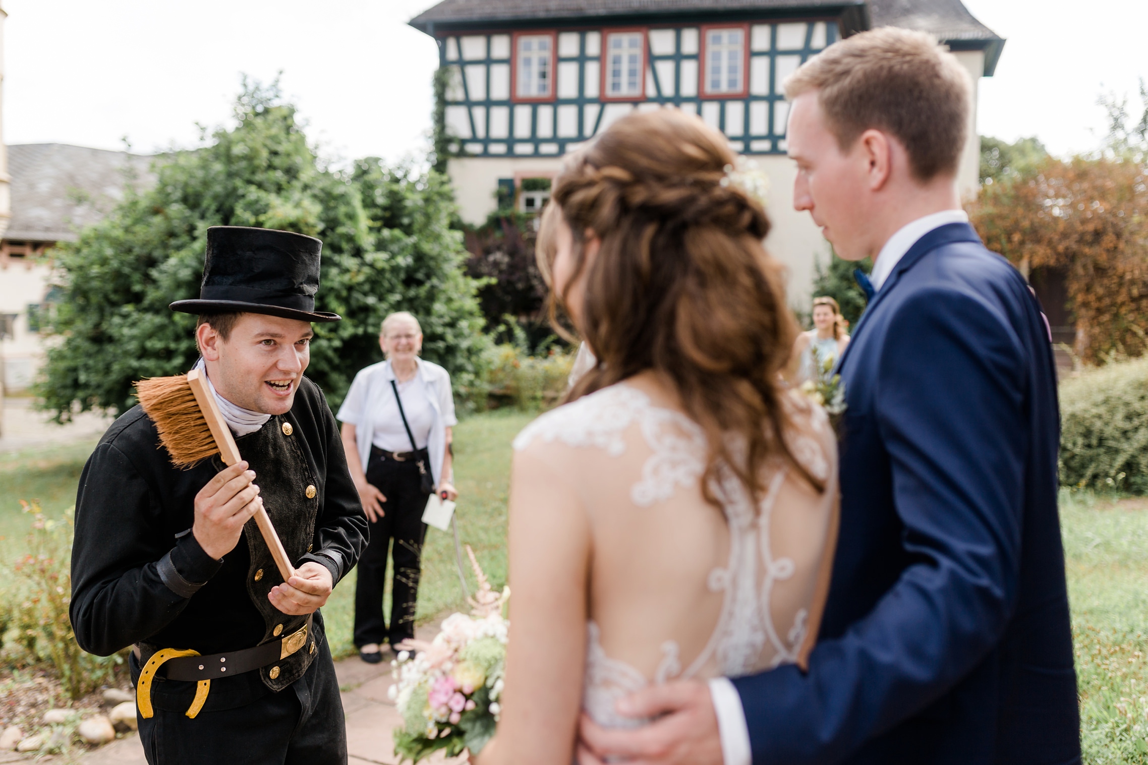 Ein Schornsteinfeger wünscht dem Hochzeitspaar viel Glück und übergibt verschiedene Gegenstände.