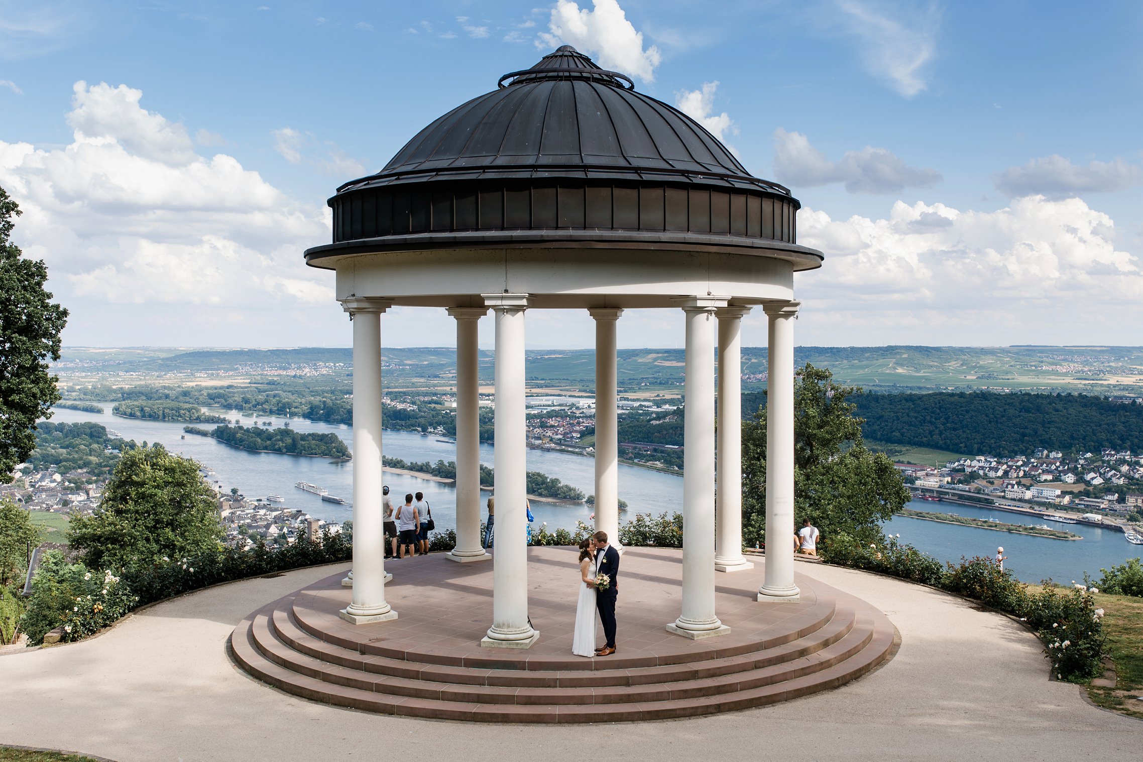 Blick über die Rheinebene mit einem Hochzeitspaar, welches im steinernen Pavillion neben der Seilbahn von Rüdesheim steht.