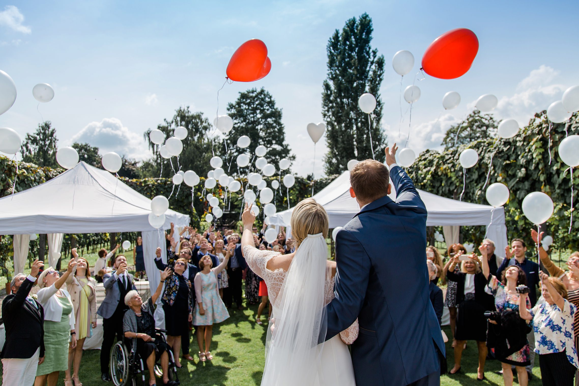 Das Hochzeitspaar lässt zusammen mit den Gästen in der RebArena im Weingut Fitz-Ritter die Luftballons steigen.