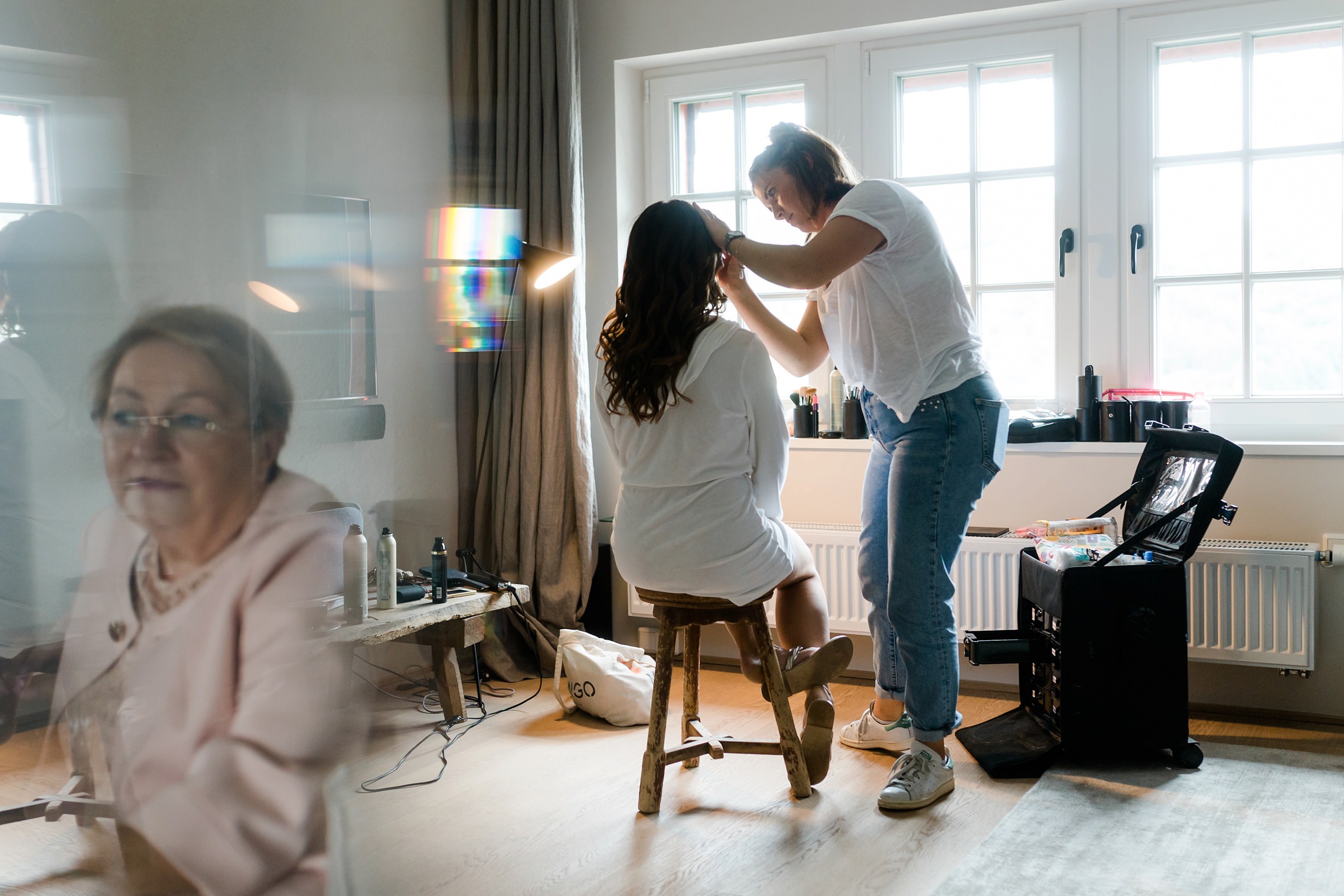 Die Braut wird von einer Verwandten beim Getting Ready beobachtet. Aufnahme mit Spiegeleffekt.