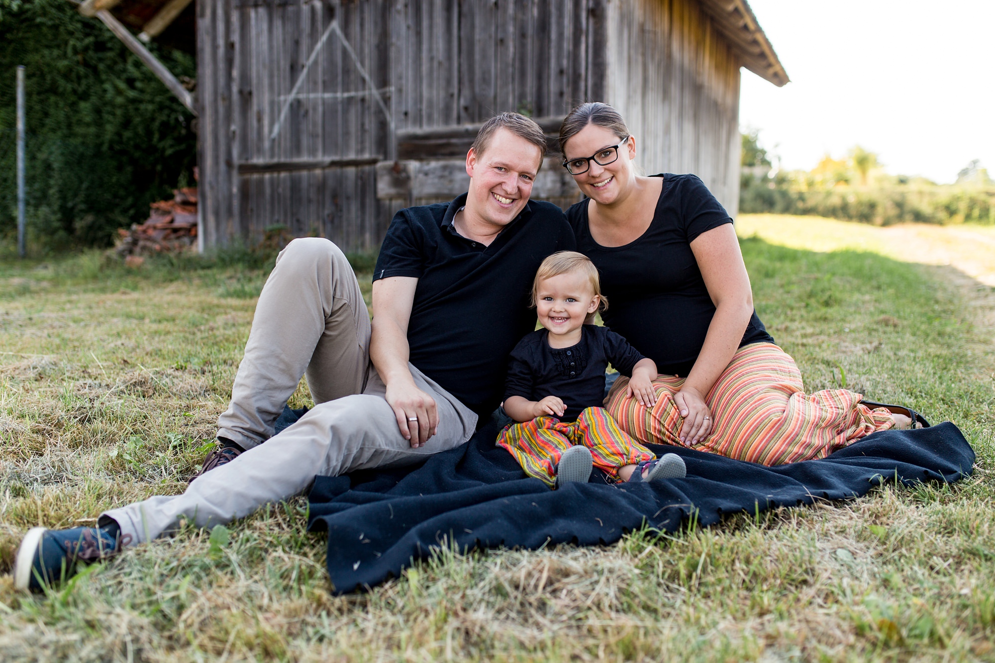 Eltern sitzen mit Tochter auf Decke