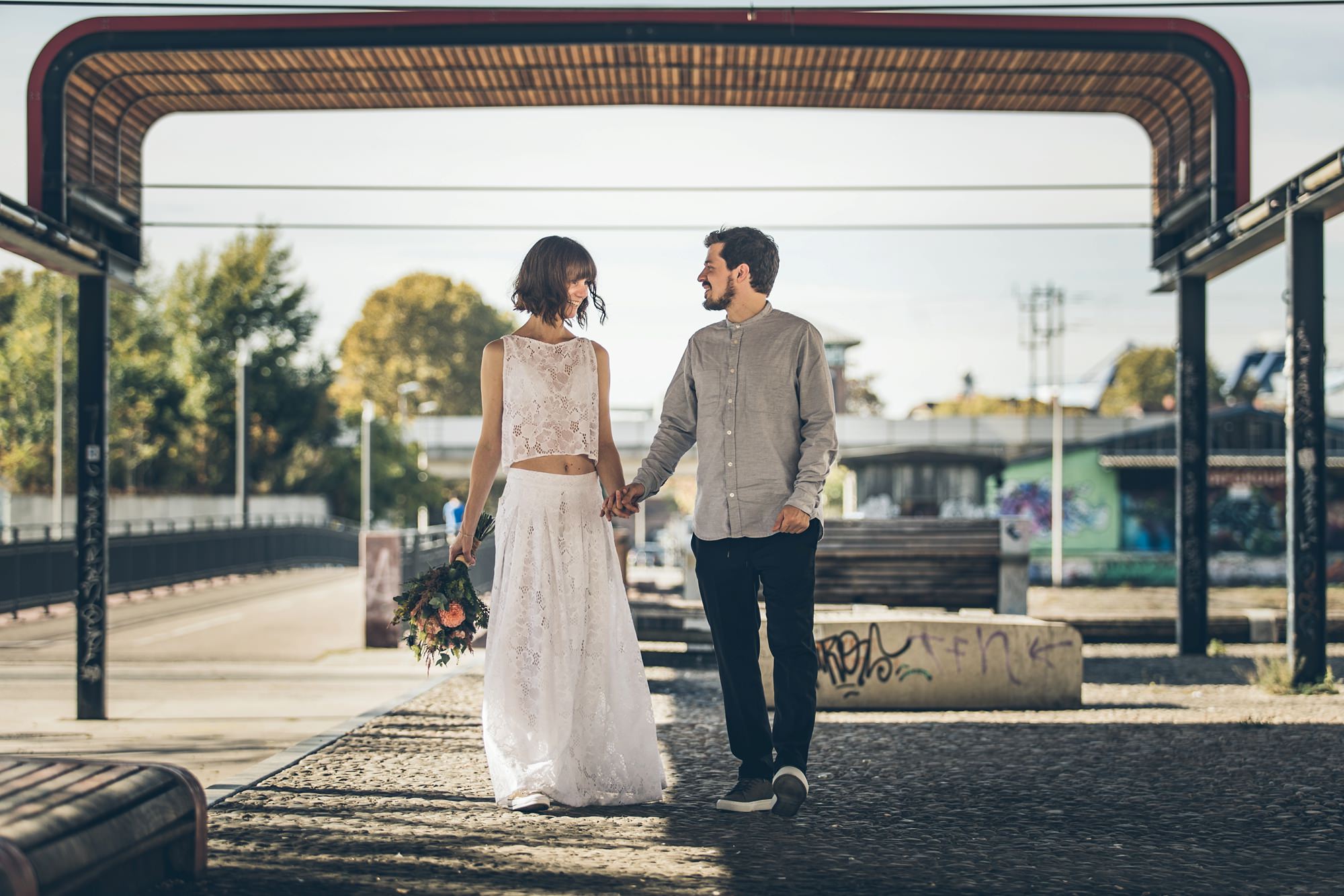 Braut und Bräutigam spazieren im Jungbusch Mannheim unter einem Holzdach