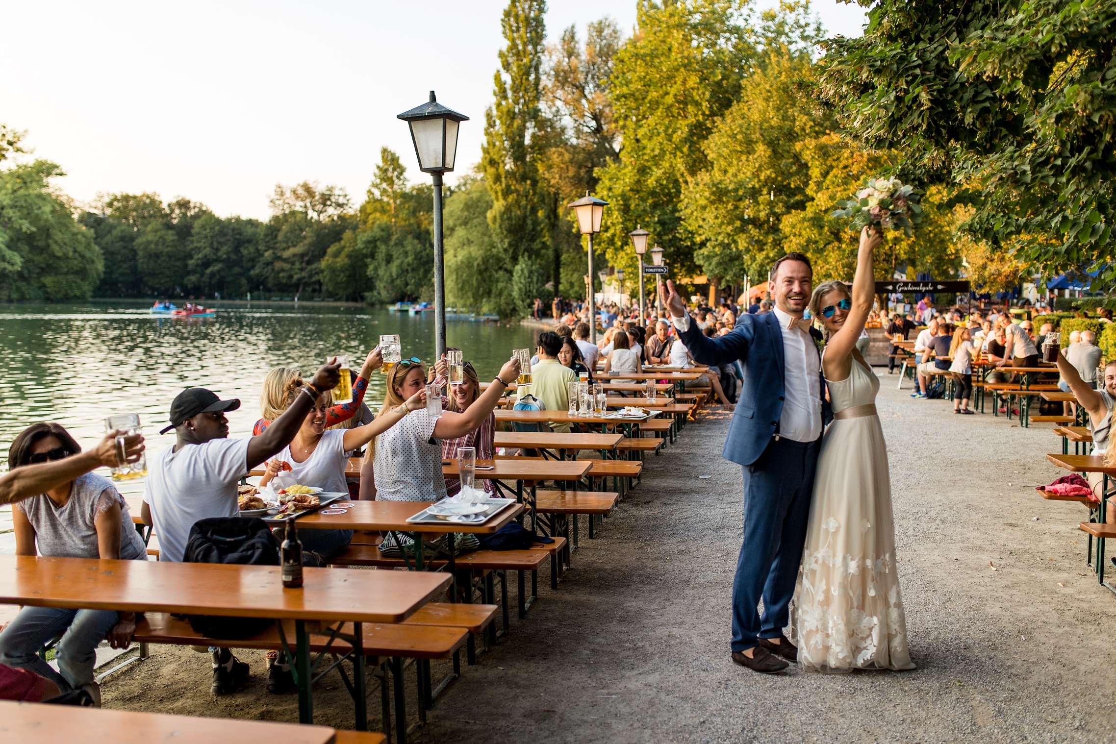 Hochzeitspaar lässt sich von Gästen bei Hochzeit im Englischen Garten in München feiern