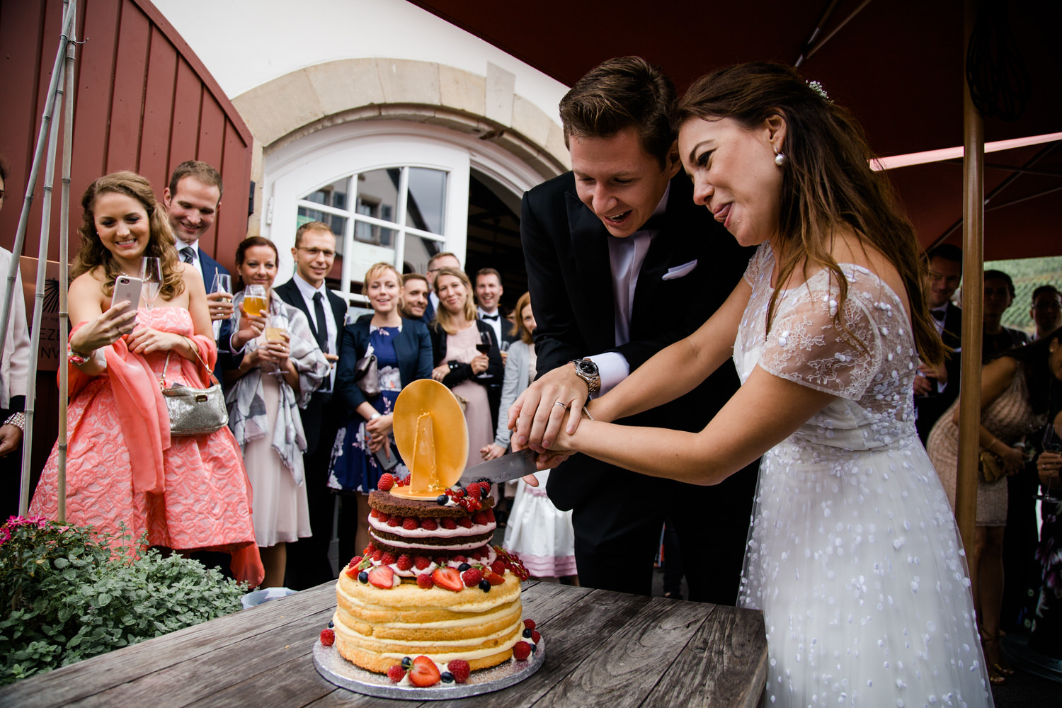 Lustiges Hochzeitspaar schneidet die Hochzeitstorte bei der Hochzeitsreportage an