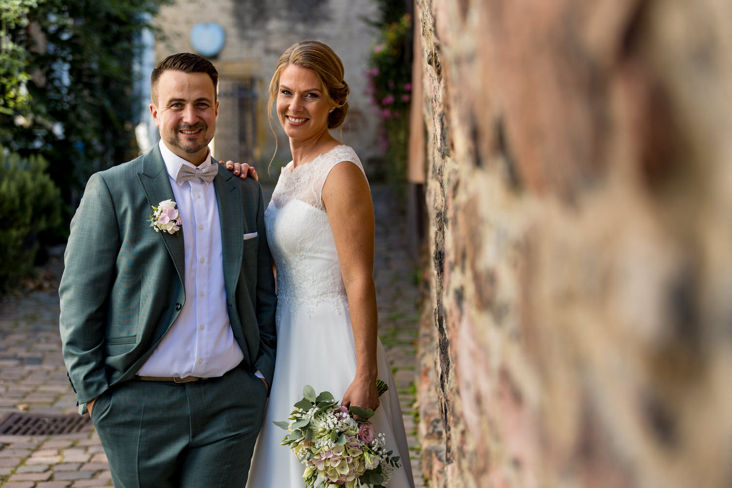 Hochzeitspaar neben einer alten Steinmauer in Speyer.