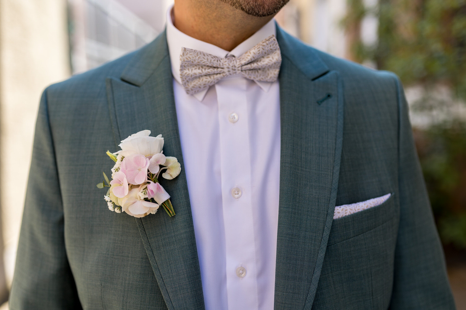 Detailaufnahme Kleidung Bräutigam mit Blumenschmuck und Fliege.